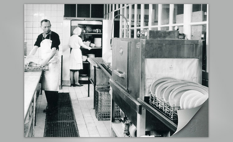 Historic commercial dishwashing area with industrial dishwasher and dish racks – early technology for efficient cleaning in professional kitchens.