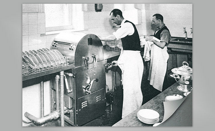 Historic image of a commercial dishwashing area with large Hobart dishwasher and dish racks – early technology for efficient cleaning in professional kitchens.