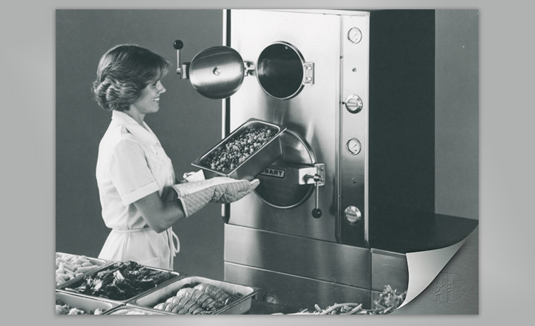 Historic image of a professional kitchen with Hobart steam cooker and trays of ingredients – early technology for efficient cooking and food preparation.
